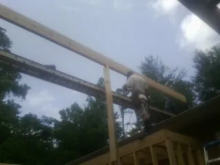 Carpenter setting a ridge beam over a new addition frame — Ice Dam Removal by Roofing Brothers in Foosland