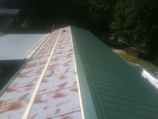 Old rusted panels beside newly installed green metal roofing — Wind Damage Roof Repair by Roofing Brothers in Foosland