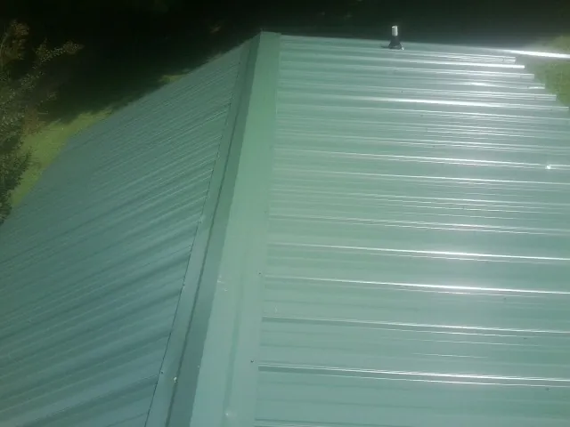 New green metal panels meeting at the ridge of a roof — Flat Roof Repair work by our crew in Foosland