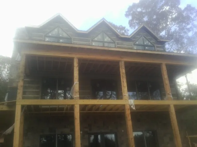 Dormers and porch framing on a large log home under construction — Roof Coating work by our crew in Foosland