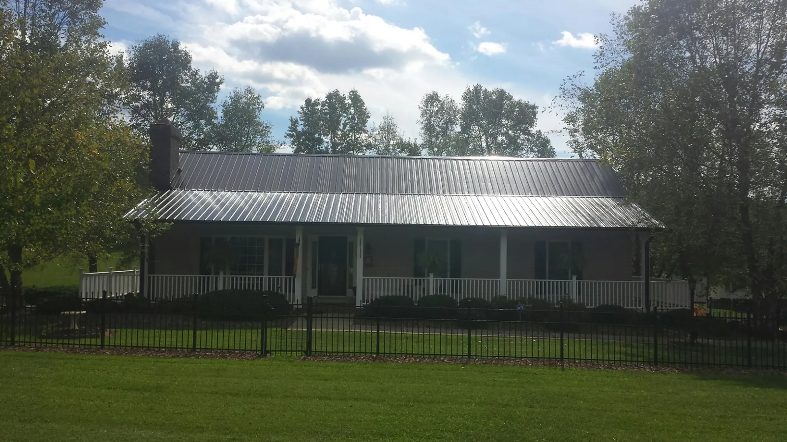 Gray metal roof on a brick ranch with a full width front porch — Gutter Guard Installation work by our crew in Foosland