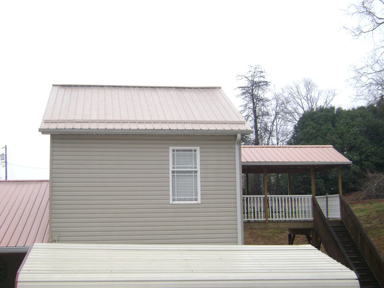 Tan metal roofs on a two story addition and attached porch, from a Roof Replacement job in Foosland