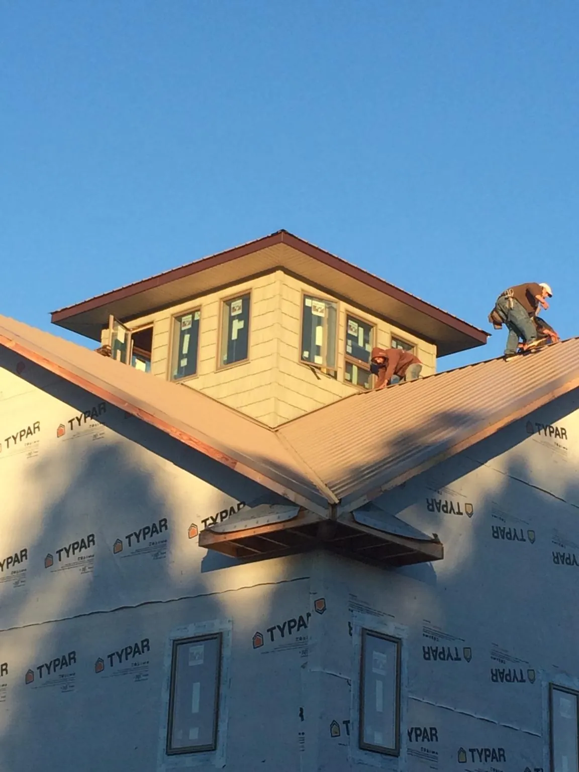 Roofers working around a rooftop cupola on a new metal roof at sunset — Roof Waterproofing in Foosland by Roofing Brothers